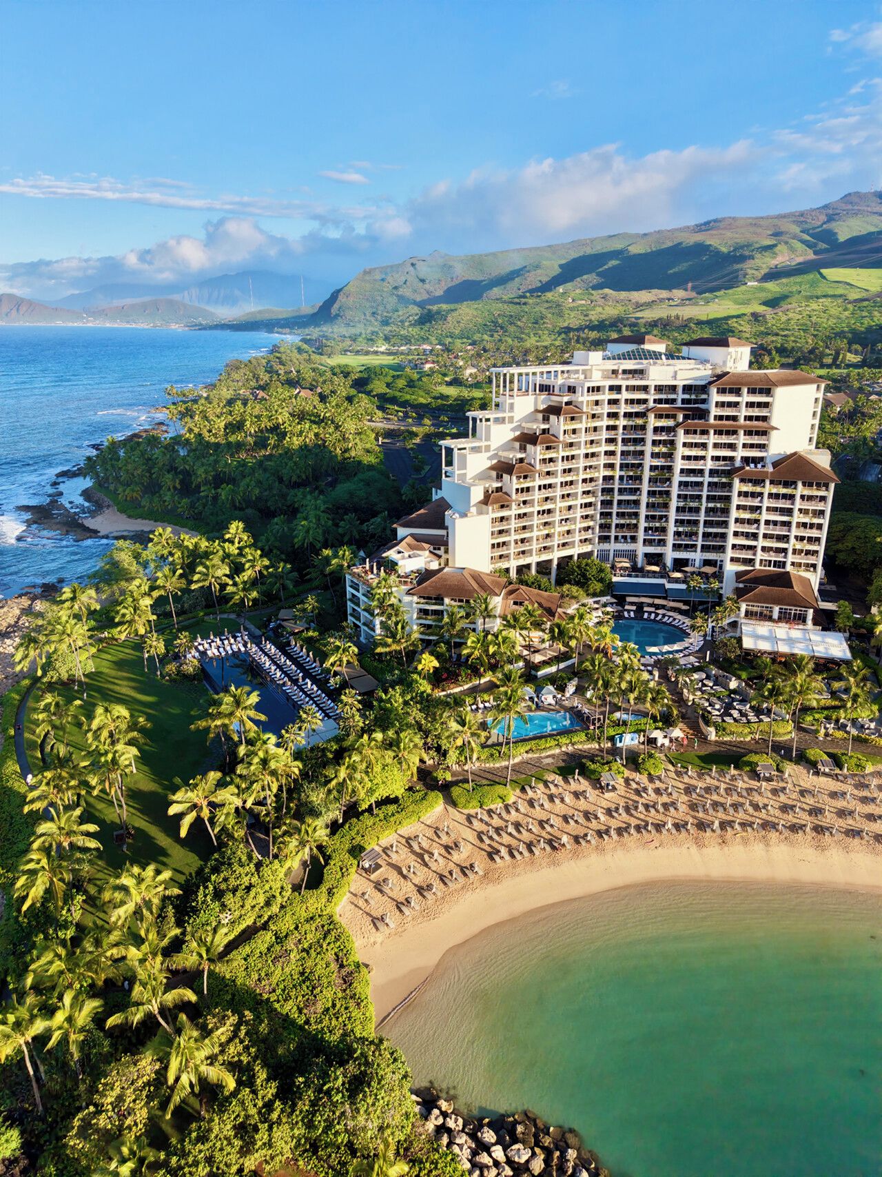 A resort with a large building, a pool, and a beach.