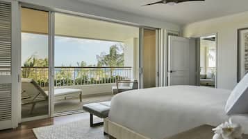 Un dormitorio con una cama grande, un balcón con vistas a palmeras y un ventilador de techo.