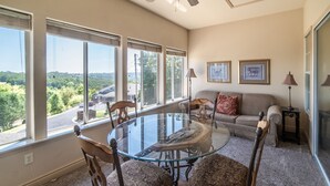 A living room with a glass-top table surrounded by four chairs, a sofa with patterned cushions, and two framed pictures on the wall. - Thousand Hills Golf Resort (Branson)