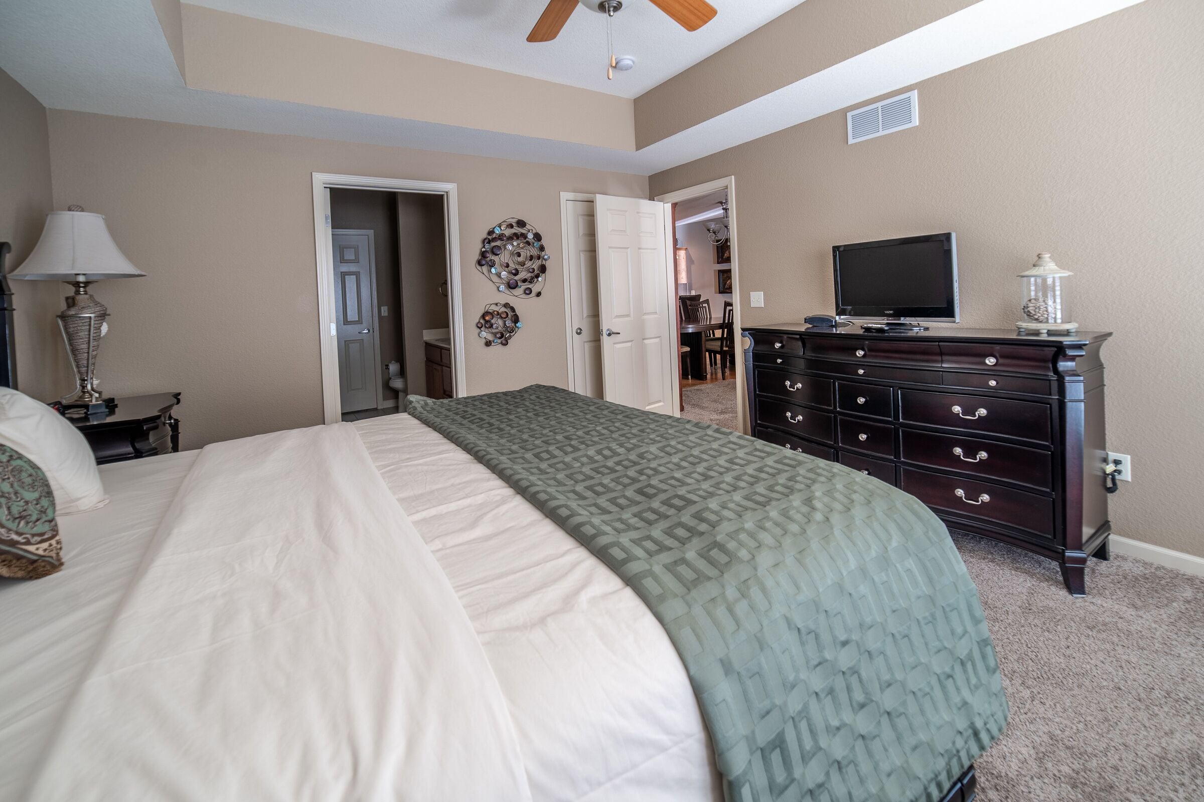 A bedroom with a bed, dresser, lamp, and television.