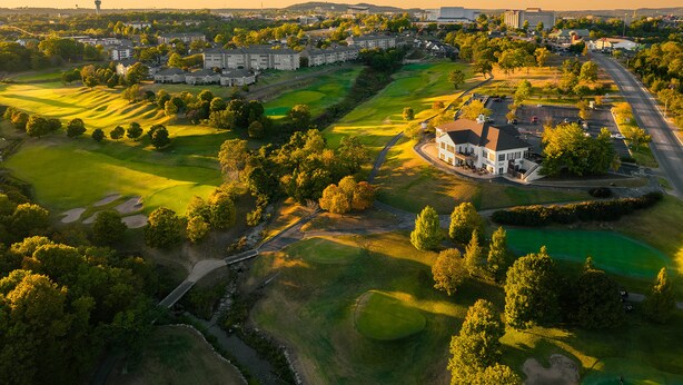 A golf course with a clubhouse, surrounded by residential buildings and a highway. - Thousand Hills Golf Resort (Branson)