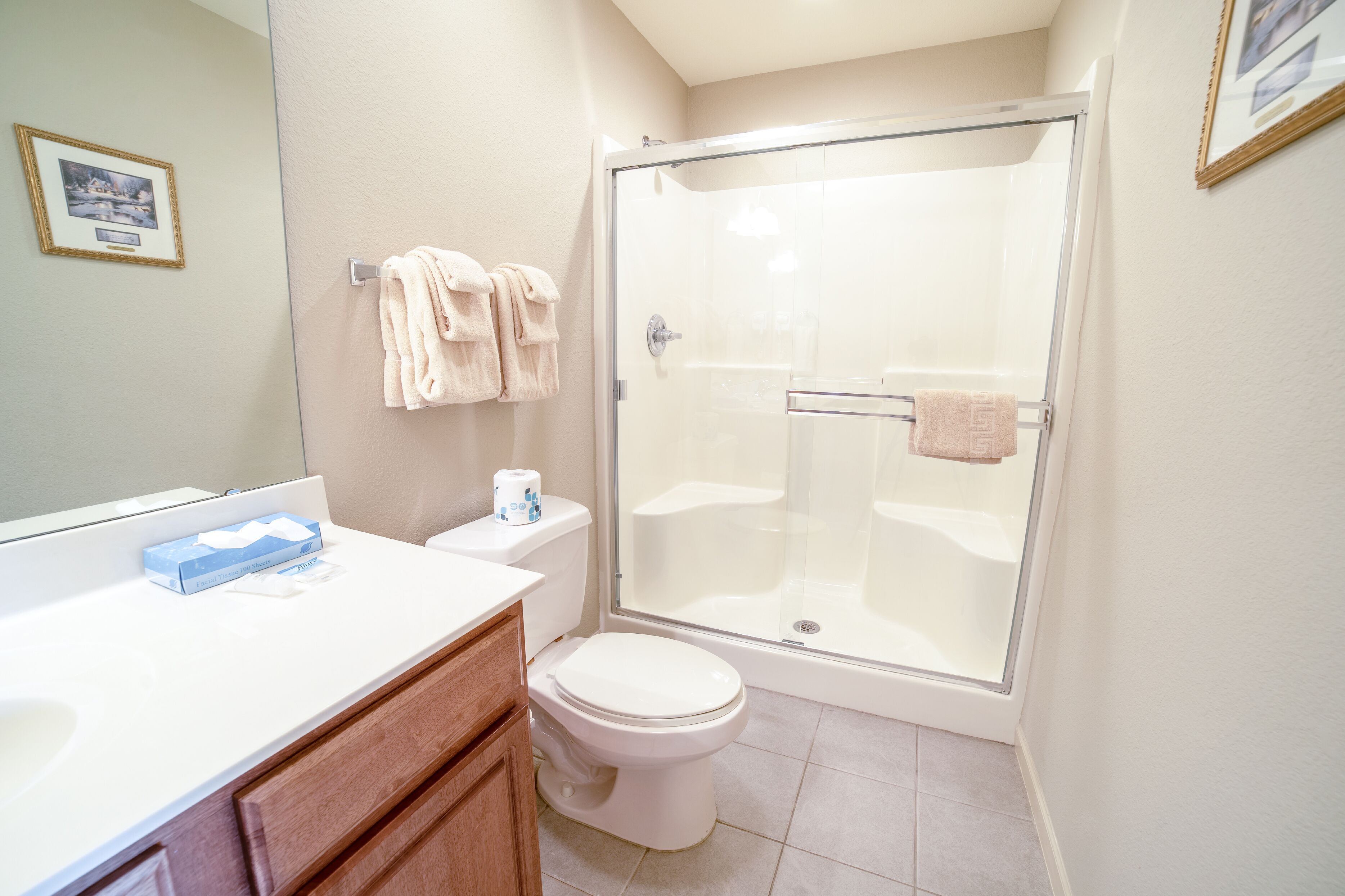 A bathroom with a toilet, a glass-enclosed shower, a sink with a mirror, and a towel rack.