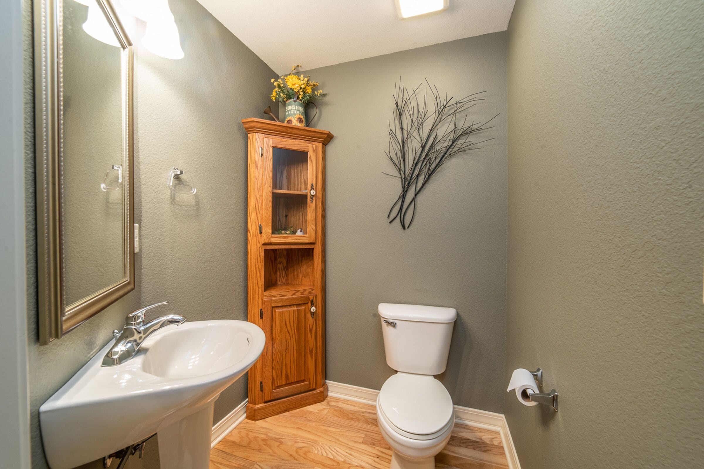 Un baño con un mueble de madera, un lavabo blanco y un inodoro.