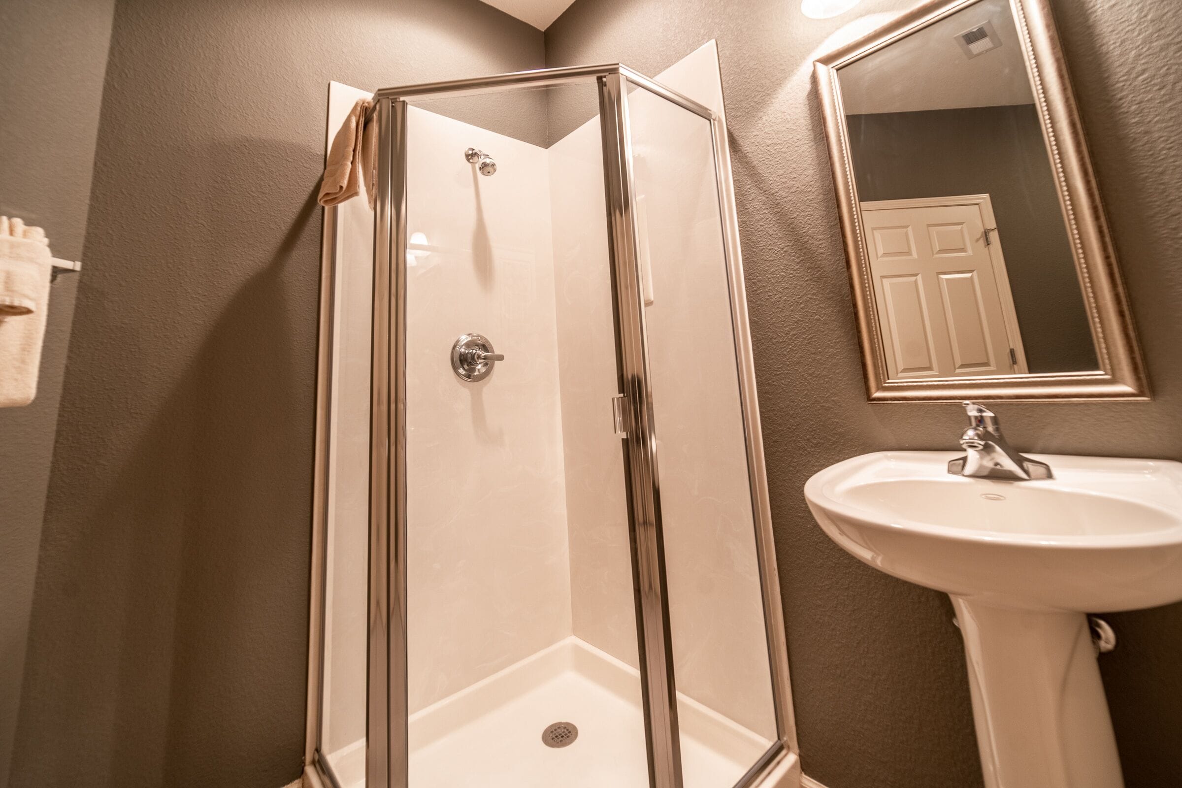 Une salle de bain avec une douche à parois de verre, un lavabo blanc et un miroir.