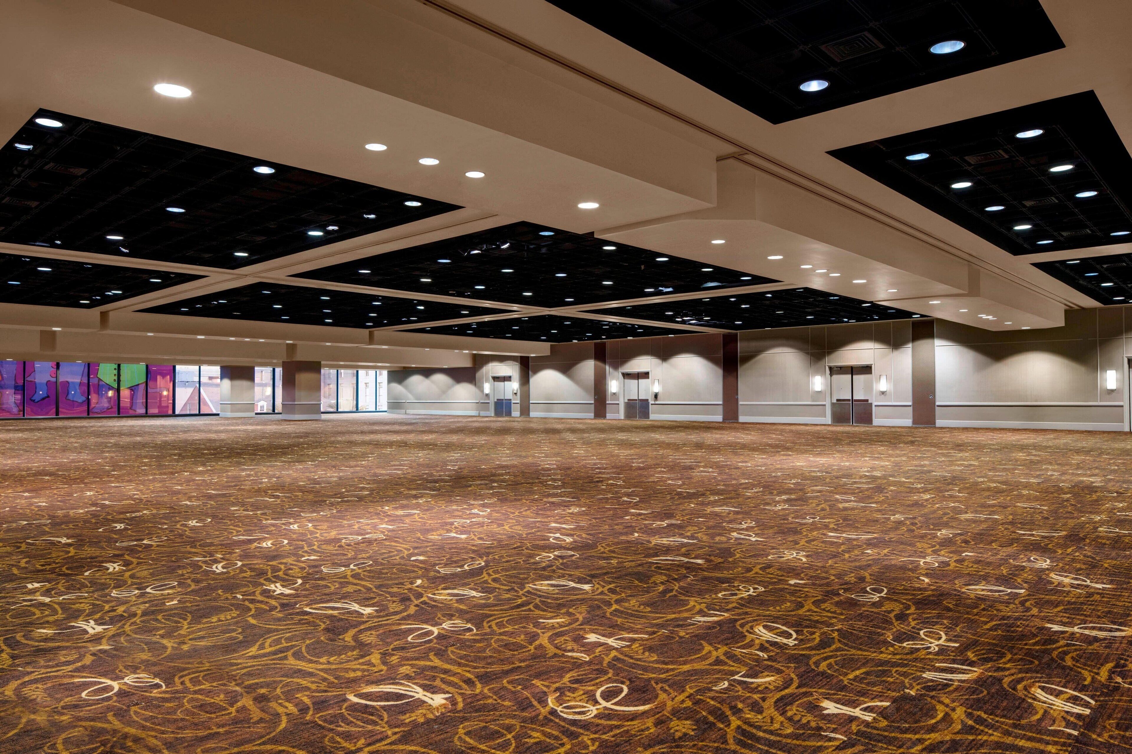 A spacious hall with a patterned carpet, recessed lighting, and a modern ceiling design.