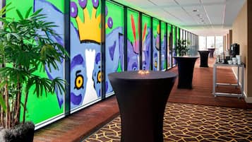 A hallway with colorful murals, a round table, and potted plants.