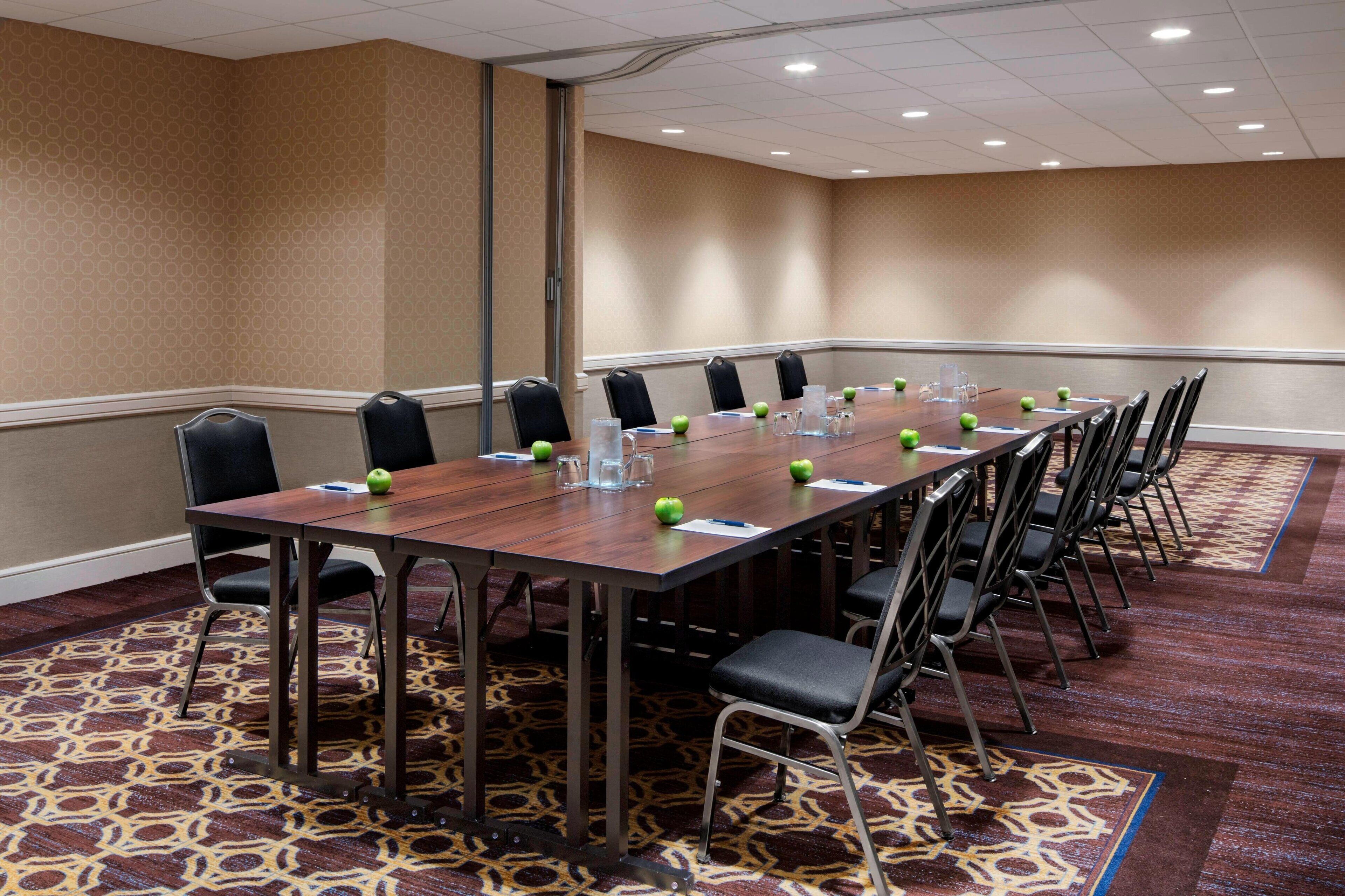 A conference room with a long table, chairs, and a patterned carpet.