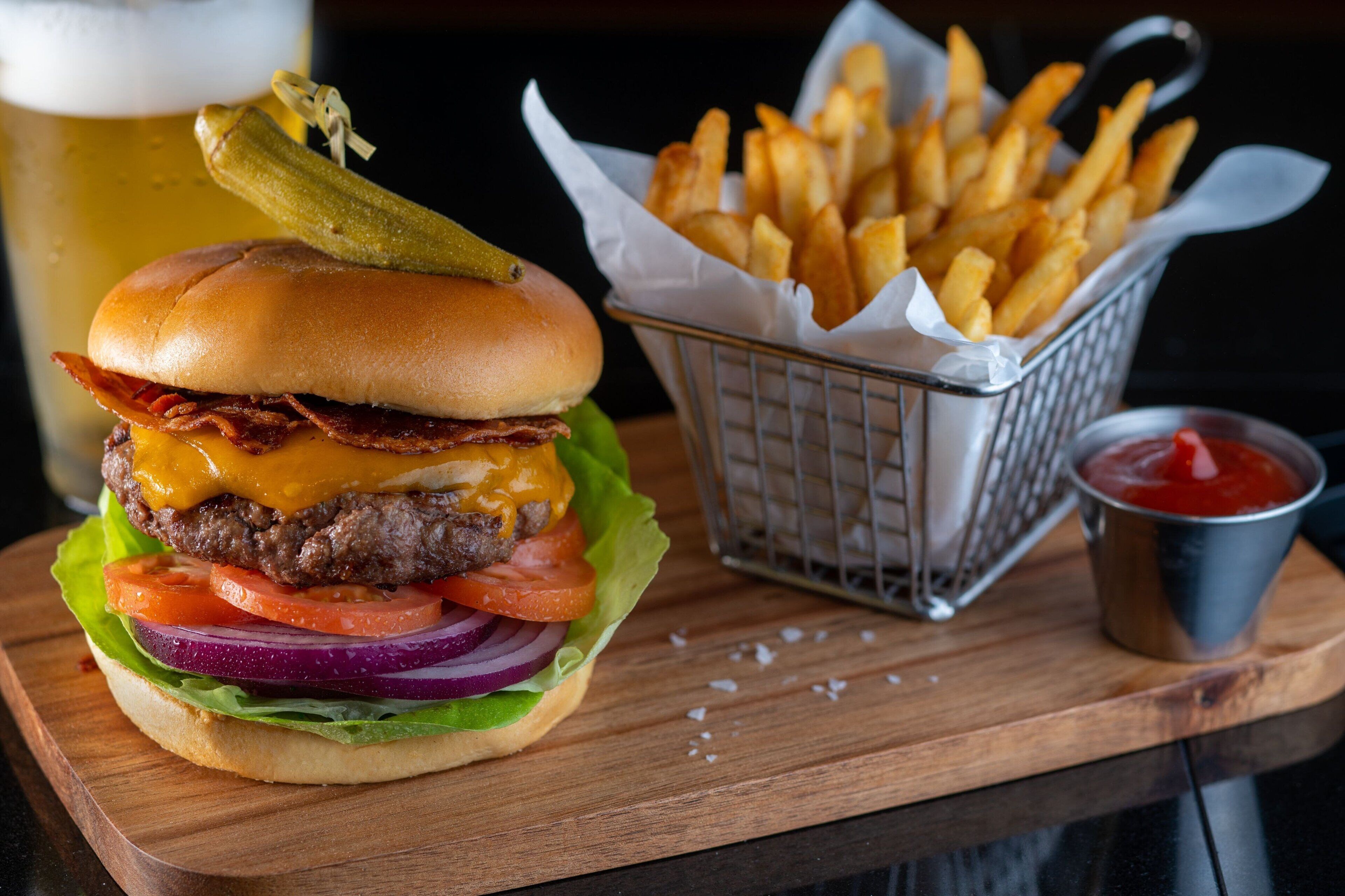 A burger with fries and ketchup on a wooden board.