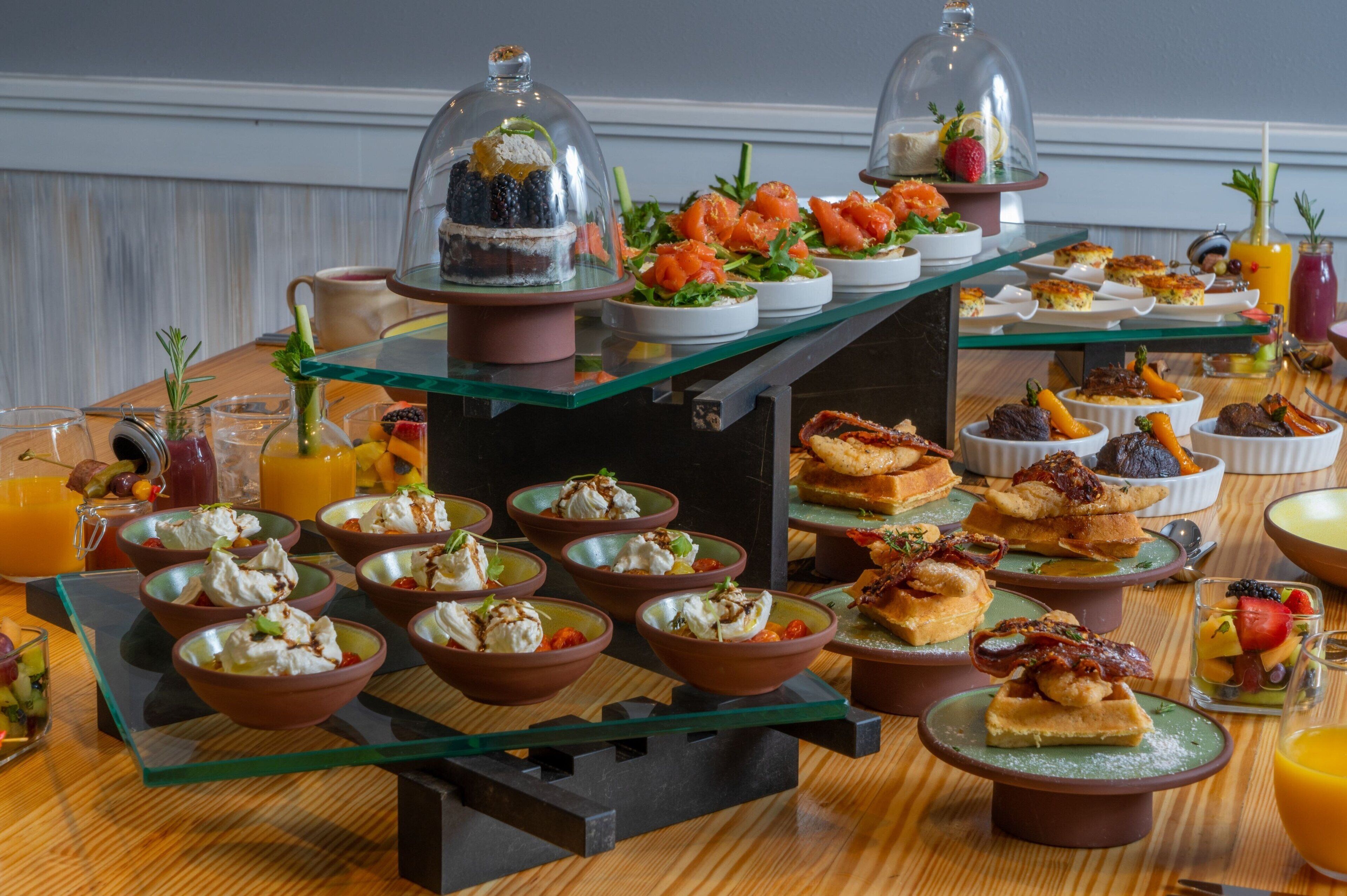 Un bufé con diversos platos y bebidas, incluyendo ensaladas, postres y refrescos.
