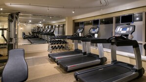 Un gimnasio con cintas de correr, mancuernas y equipo de ejercicio.