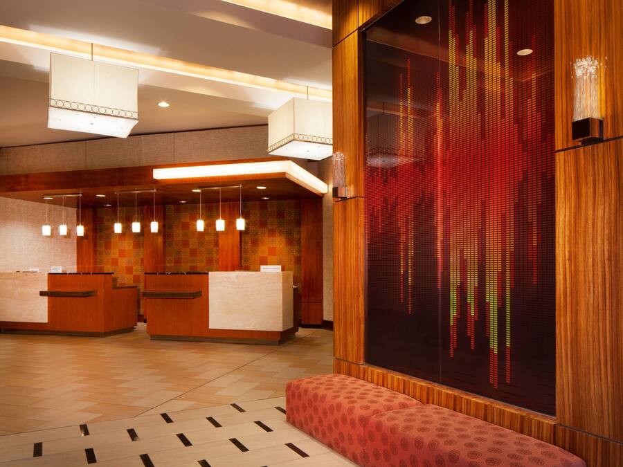 A hotel reception area with a modern design, featuring a reception desk, seating area, and a large digital display.