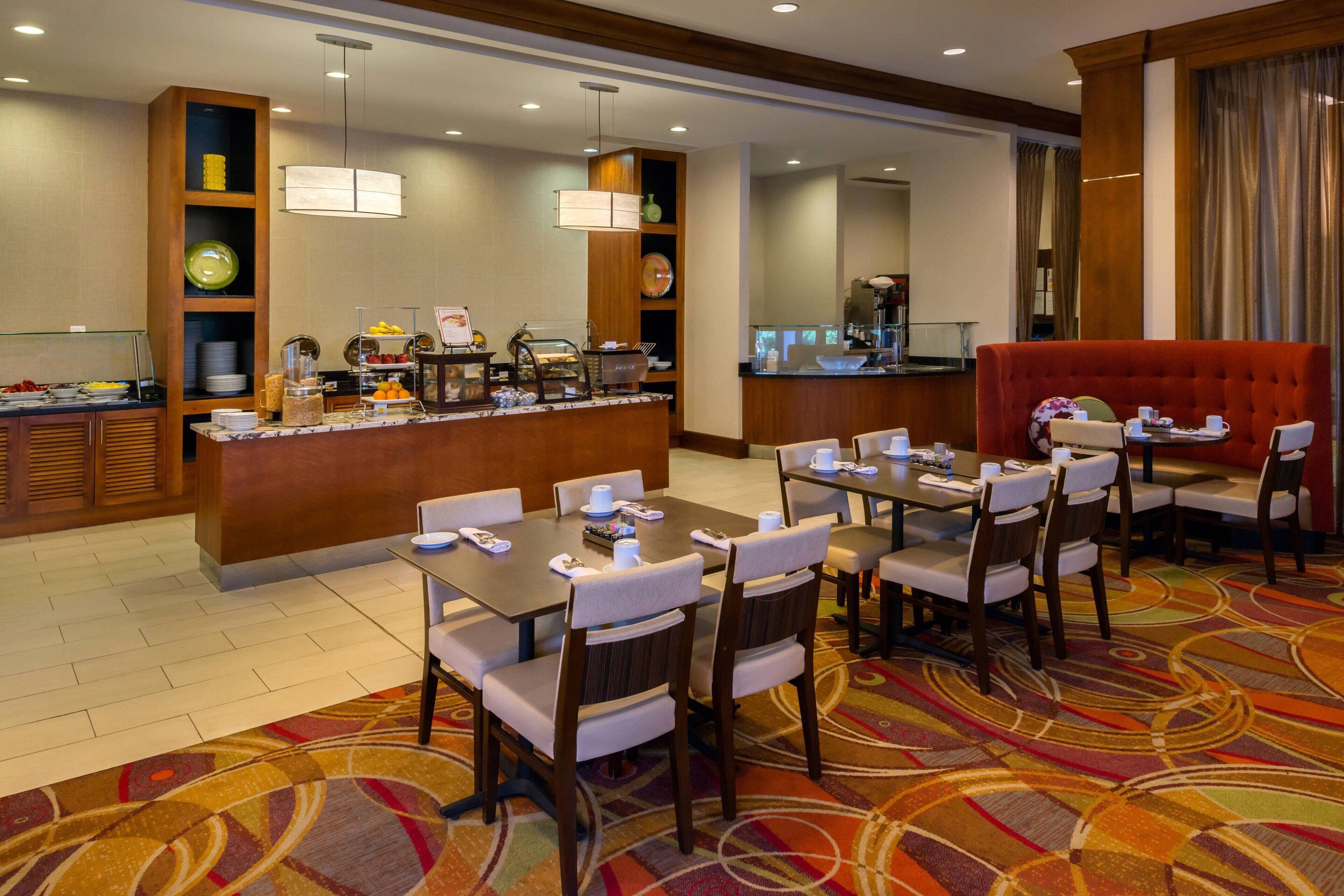 A hotel dining area with a buffet, seating arrangements, and a red booth.