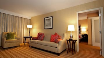 A hotel room with a sofa, armchair, two side tables, and a framed picture on the wall.