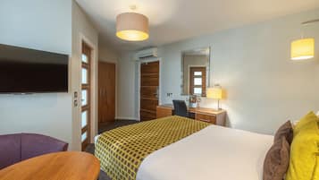 A hotel room with a bed, a desk, a chair, a television, and a wardrobe.