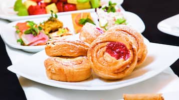 Una mesa con diversos platos que incluyen pasteles, rollitos primavera y vasos de fruta.