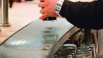 A person pouring a beverage into a glass at a bar.