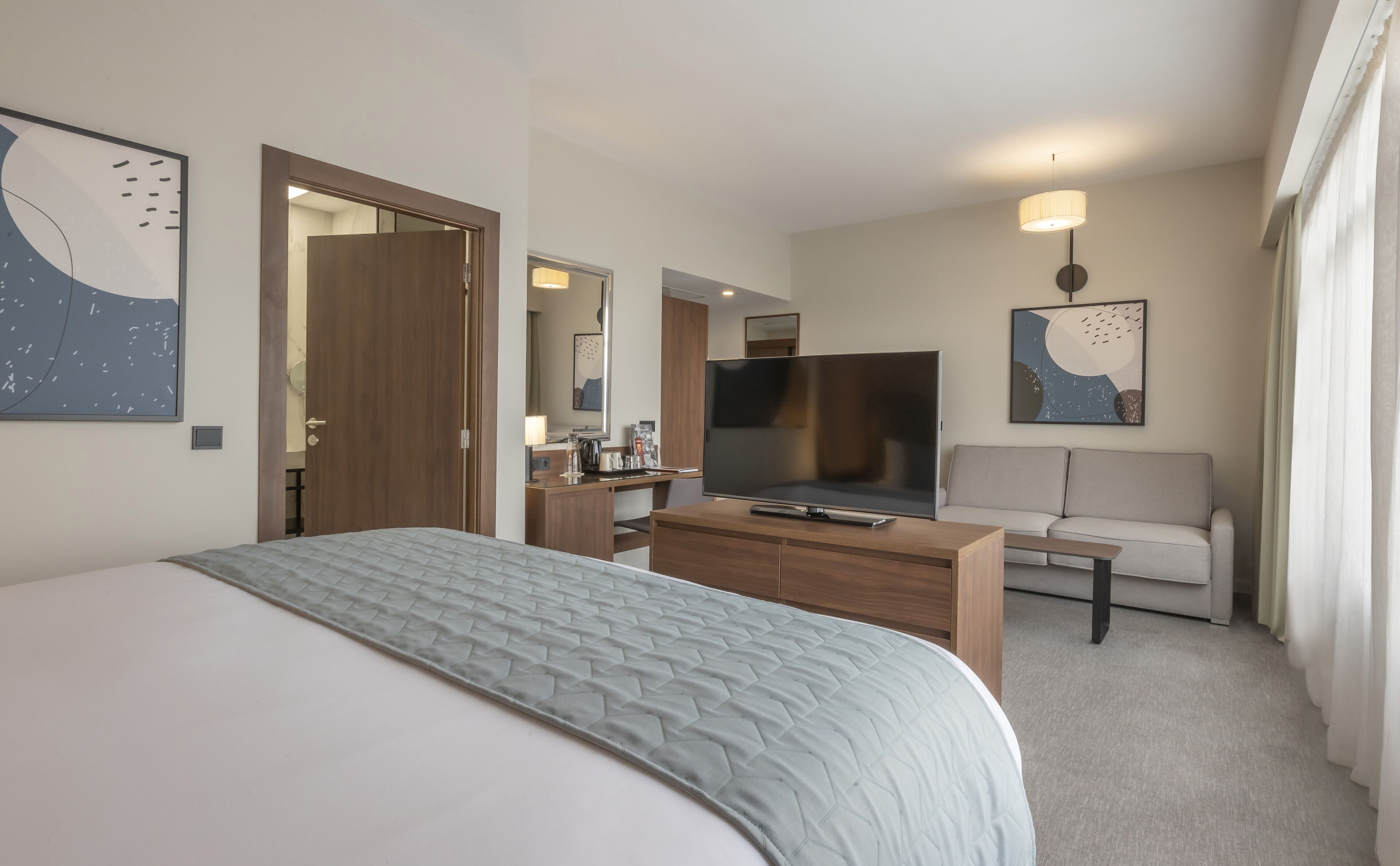 Et hotelværelse med en seng, et fjernsyn, en sofa og et sofabord.