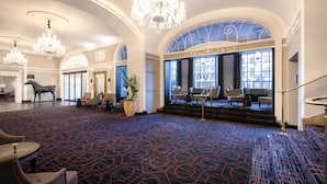 A spacious lobby with high ceilings, ornate chandeliers, and a patterned carpet.
