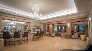 A spacious lobby with a bar area, seating arrangements, and a large chandelier.