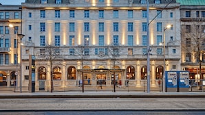A historic building with multiple floors, large windows, and a central entrance with a covered area.