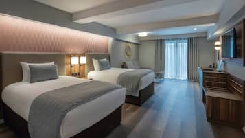 Habitación de hotel con dos camas, un escritorio, un espejo y un televisor.