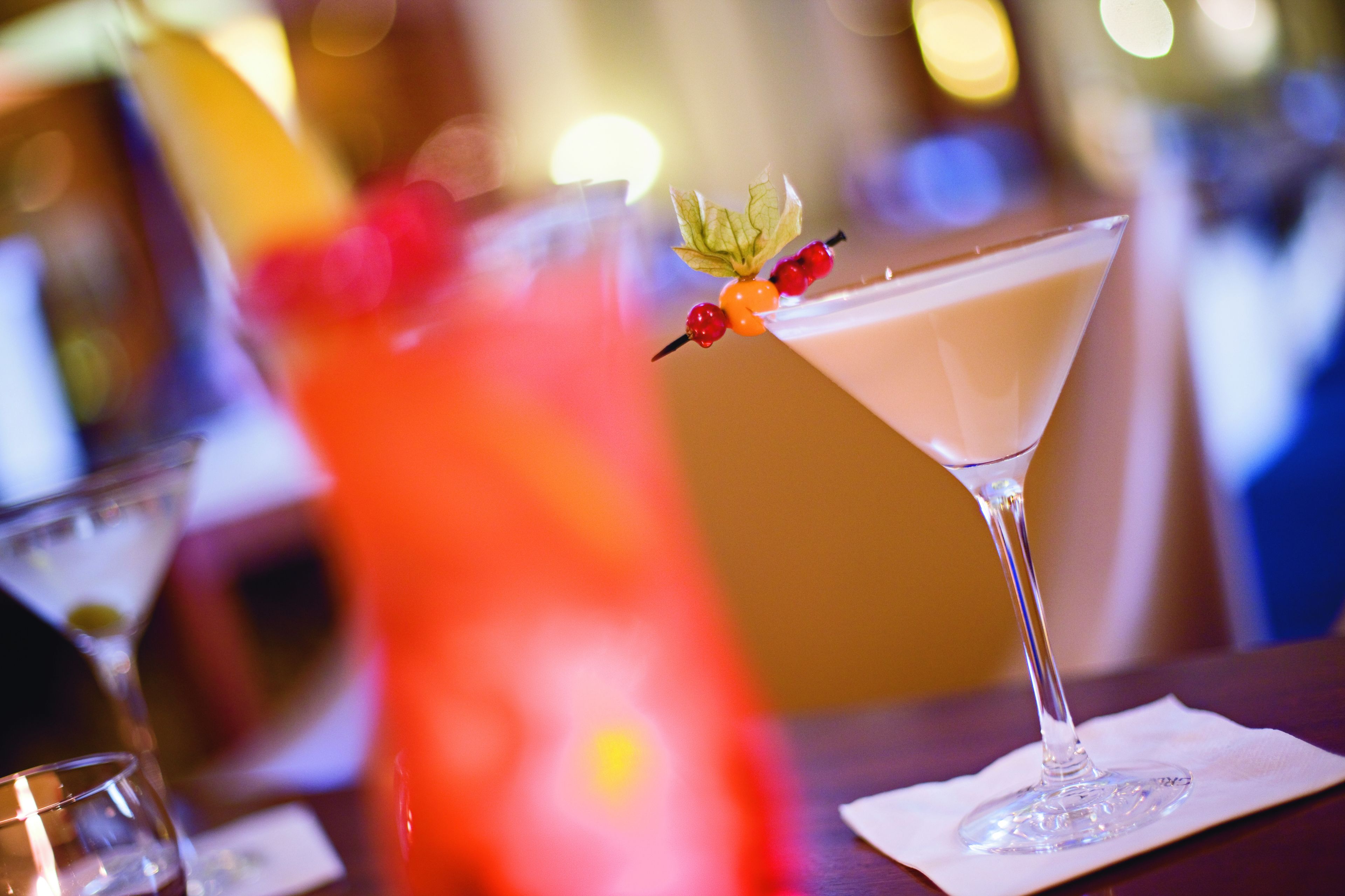 A martini glass with a garnish on a bar counter.