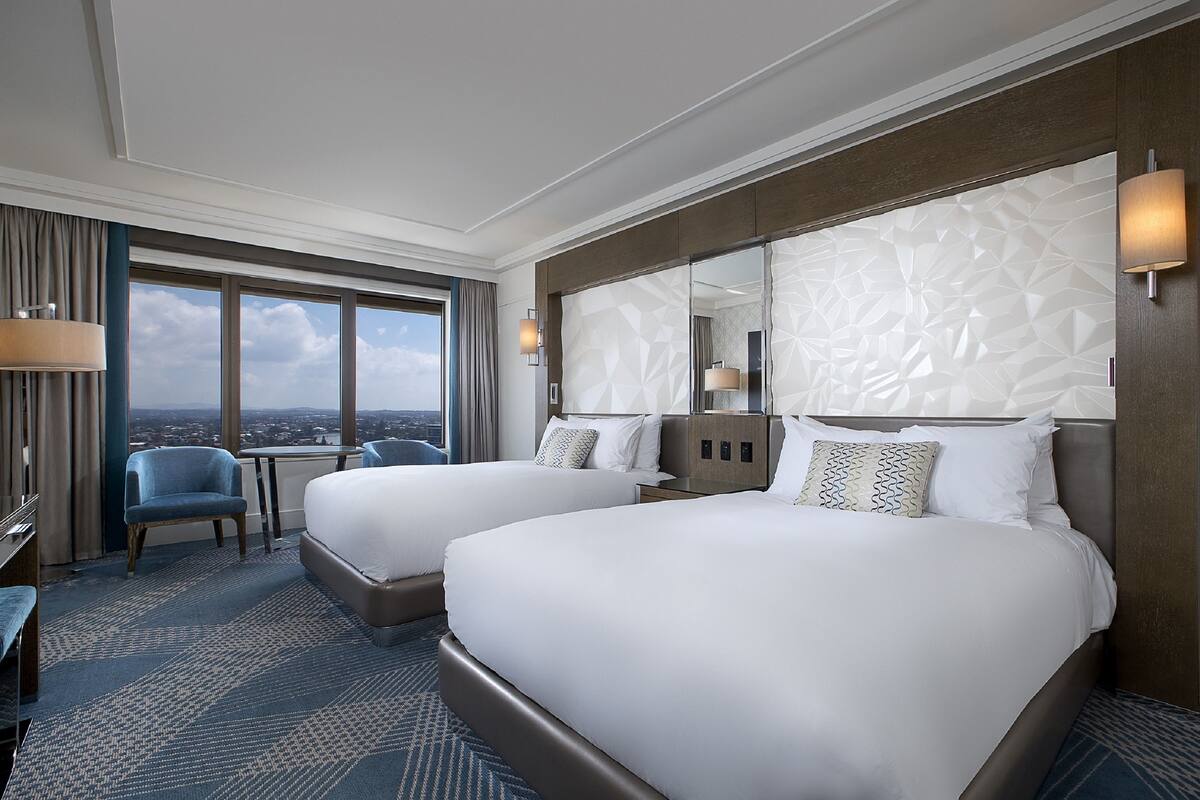 Une chambre d’hôtel avec deux lits, une vue sur la ville et une grande fenêtre.