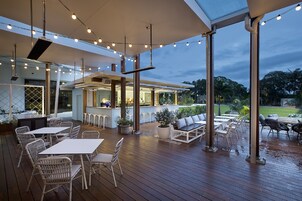 Un patio al aire libre con mesas, sillas, una zona de bar y vistas del exterior.