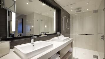 A modern bathroom with two sinks, a large mirror, and a glass-enclosed shower.