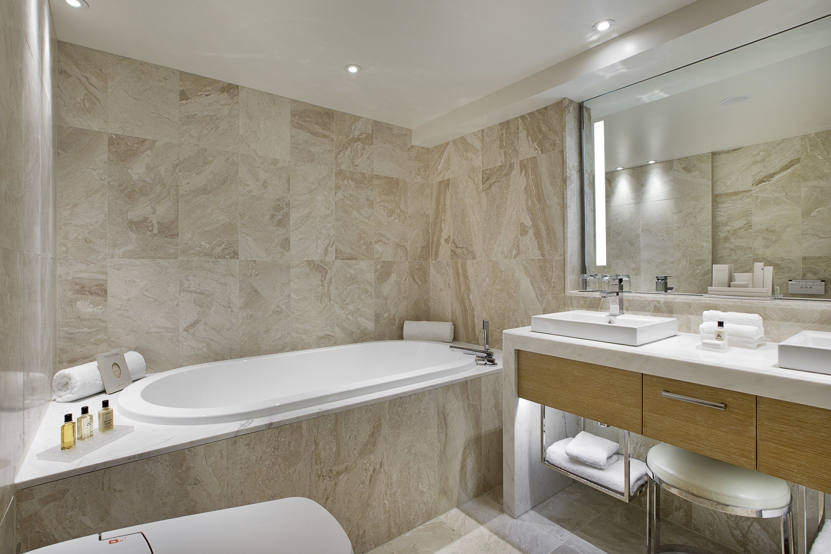 Een moderne badkamer met een vrijstaand bad, een wastafel met spiegel en een toilet.