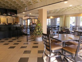 A restaurant interior with a Christmas tree, checkered floor, and bar area with bottles.