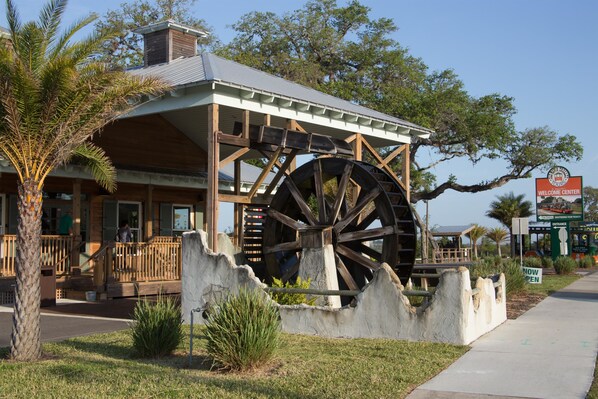 A building with a large water wheel, wooden structure, and a welcoming sign.