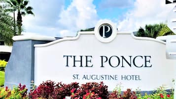 Une enseigne pour l’hôtel The Ponce St. Augustine, avec un logo circulaire, entourée de jardins aménagés.