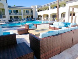 Área da piscina com mobiliário de vime e vista clara para os edifícios do hotel ao fundo.