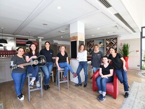 Un groupe de personnes se trouve dans un intérieur moderne, avec un coin bar, des étagères et une grande fenêtre.