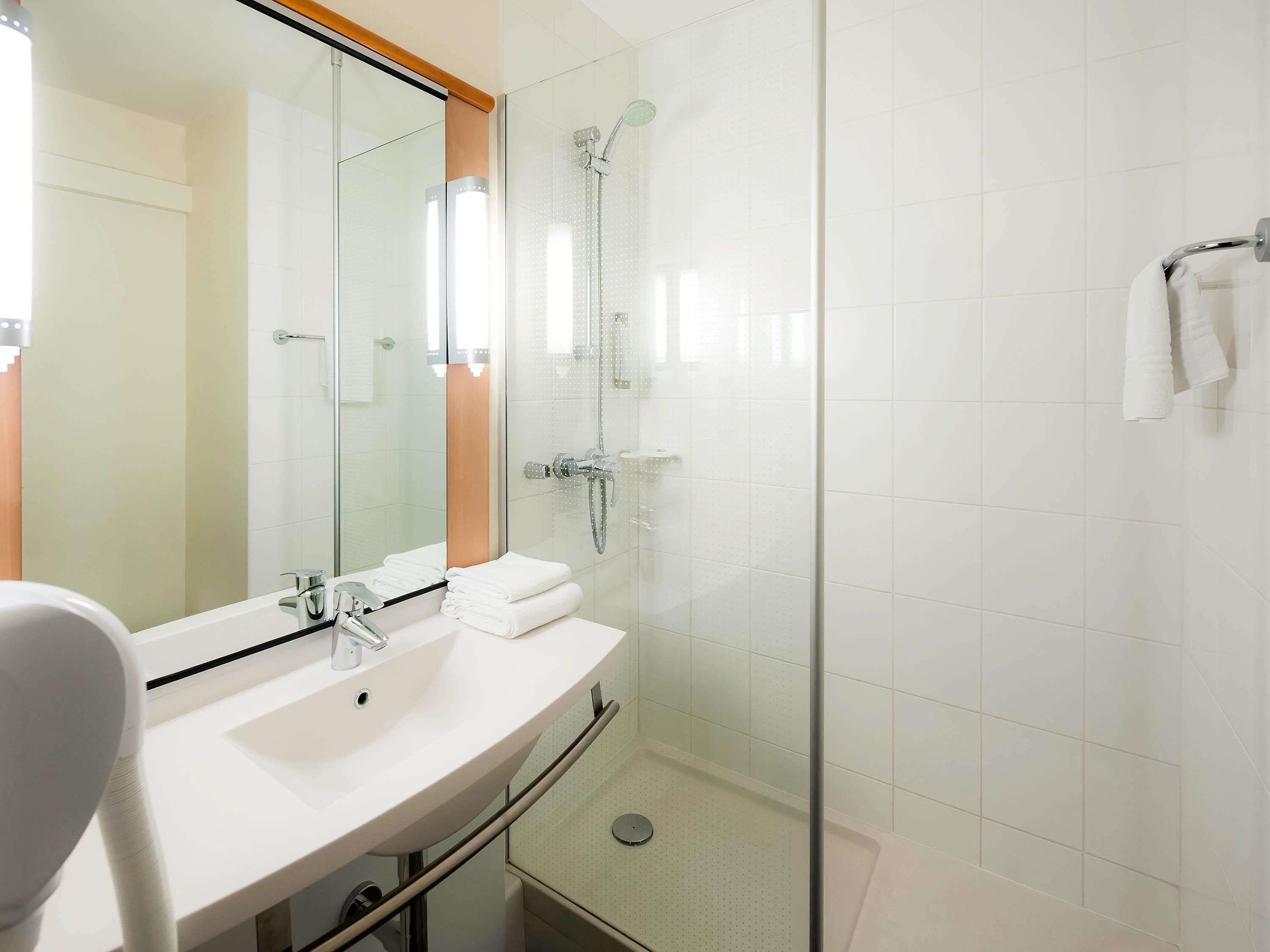 A modern bathroom with a glass shower enclosure, a white sink, and a mirror.
