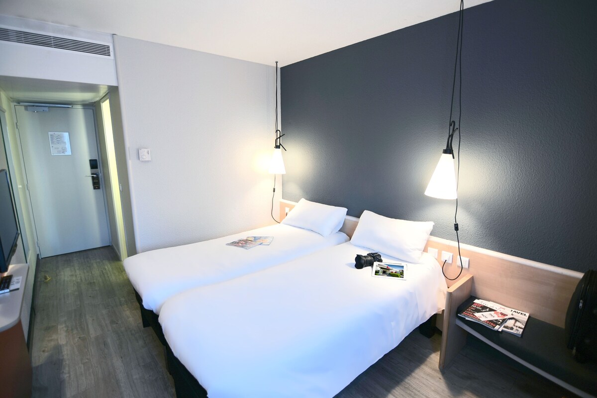 Una habitación de hotel con dos camas, un escritorio y una mesita de noche.