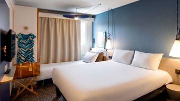 A hotel room with a large bed, a desk, a chair, a television, and a window with curtains.