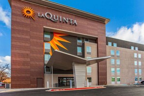 Ein La Quinta Hotel mit großem Sonnensymbol, überdachter Eingangspartei und blauem Himmel.