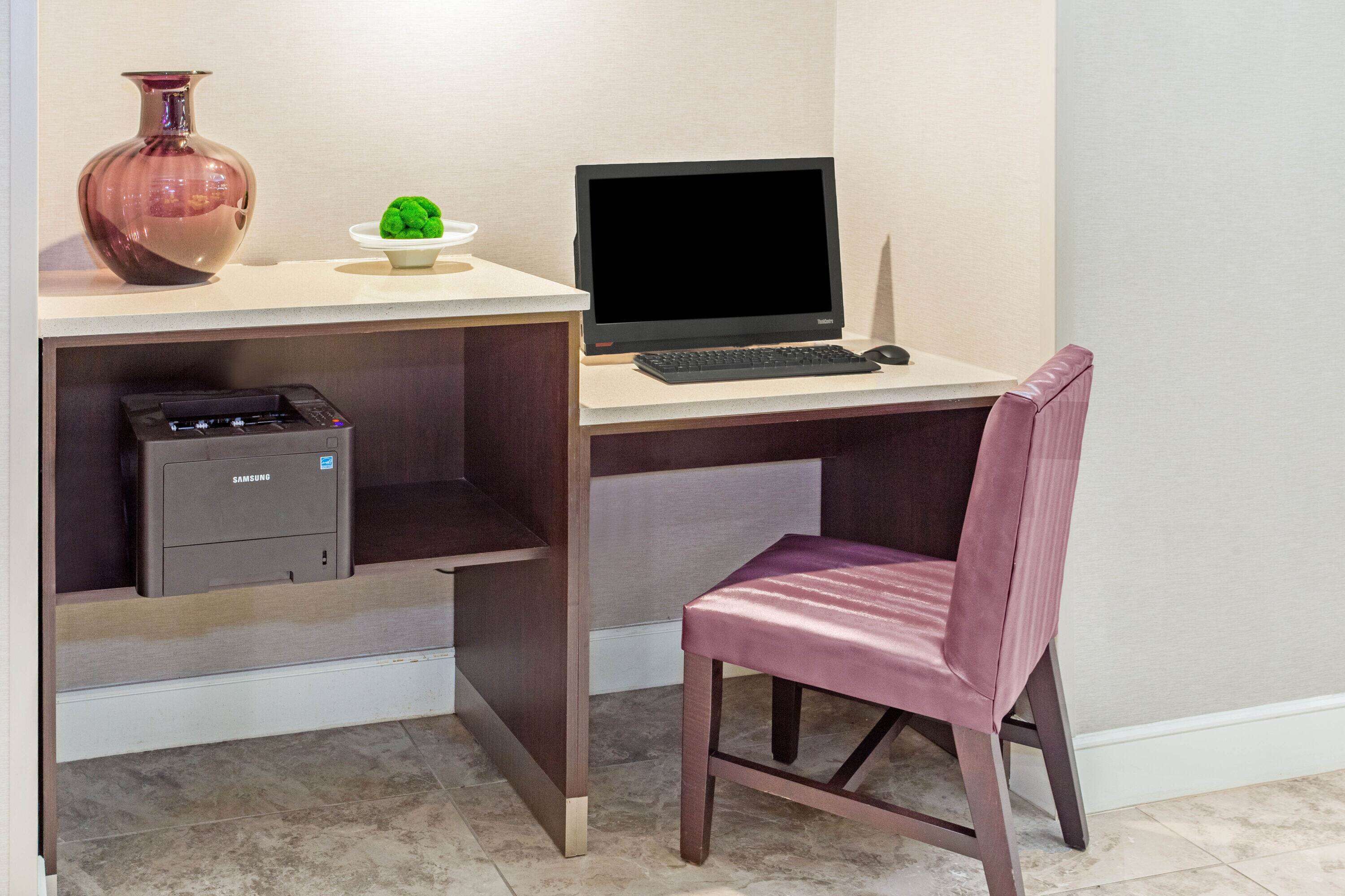Ein Schreibtisch mit einem Computer, einem Drucker und einer Vase.