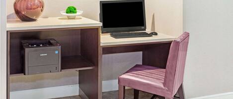 Ein Schreibtisch mit einem Computer, einem Drucker und einer Vase.