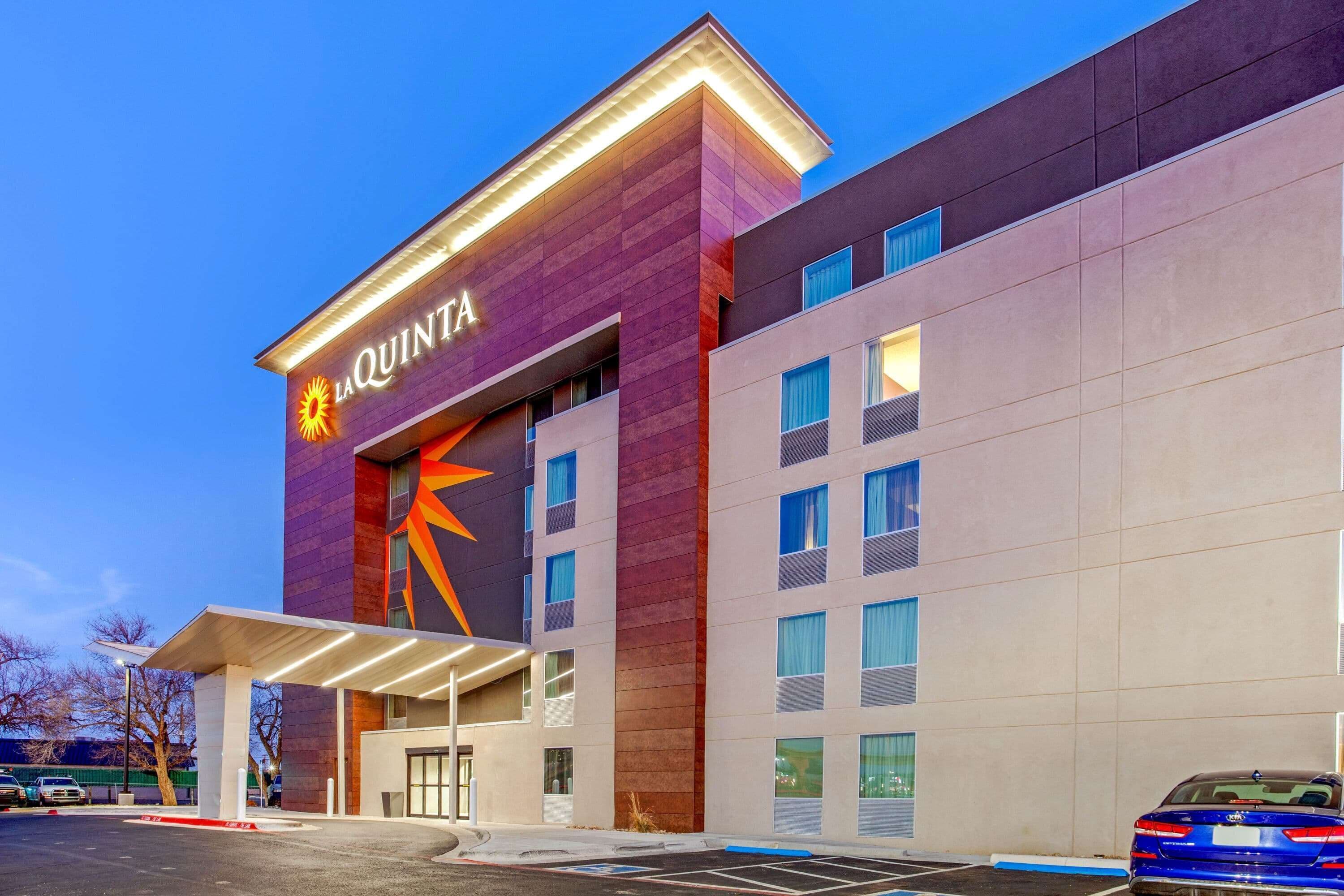 A hotel with a prominent 'LA QUINTA' sign, a modern facade, and a covered entrance area.