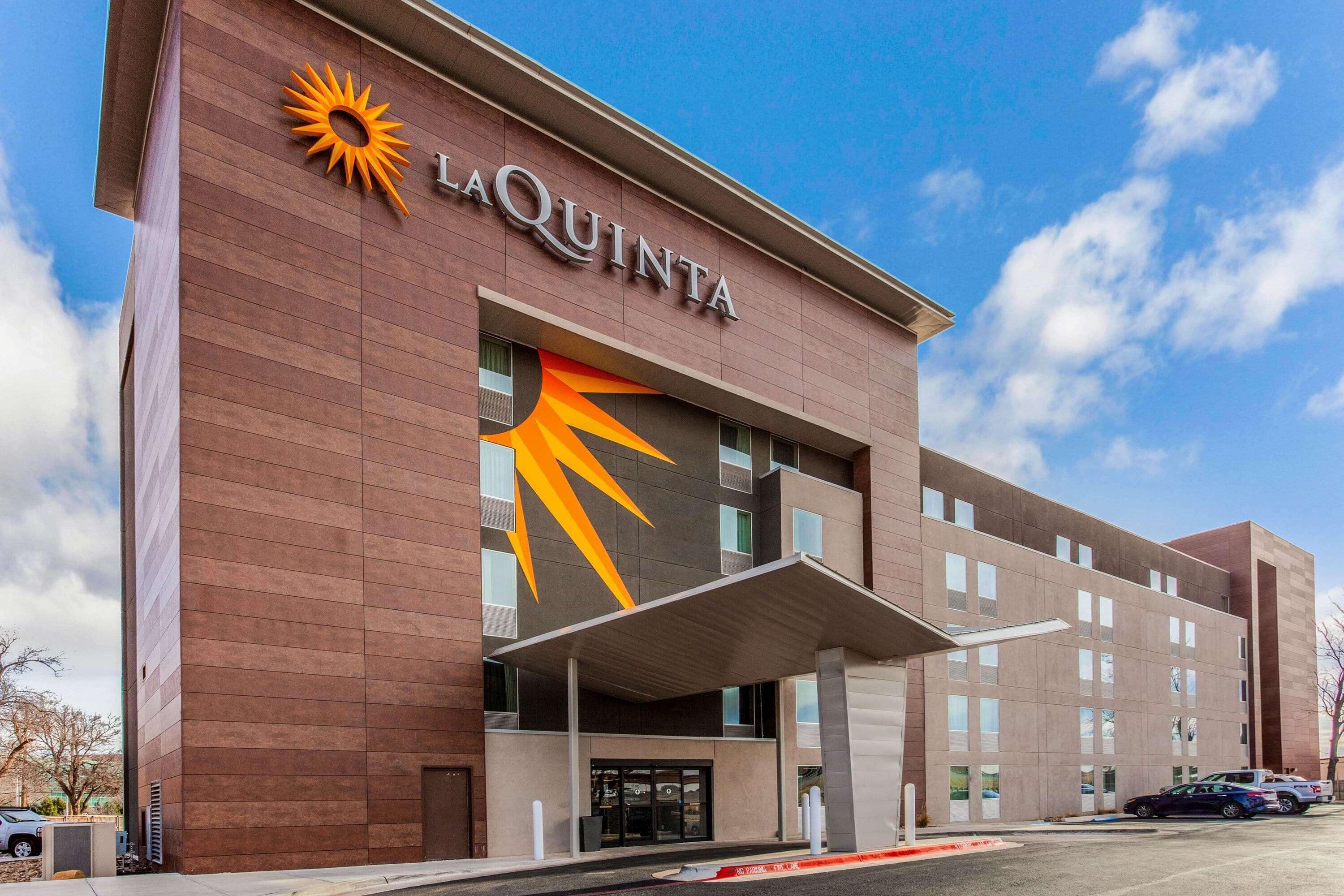 A La Quinta hotel with a modern design, featuring a prominent sun logo and a covered entrance.