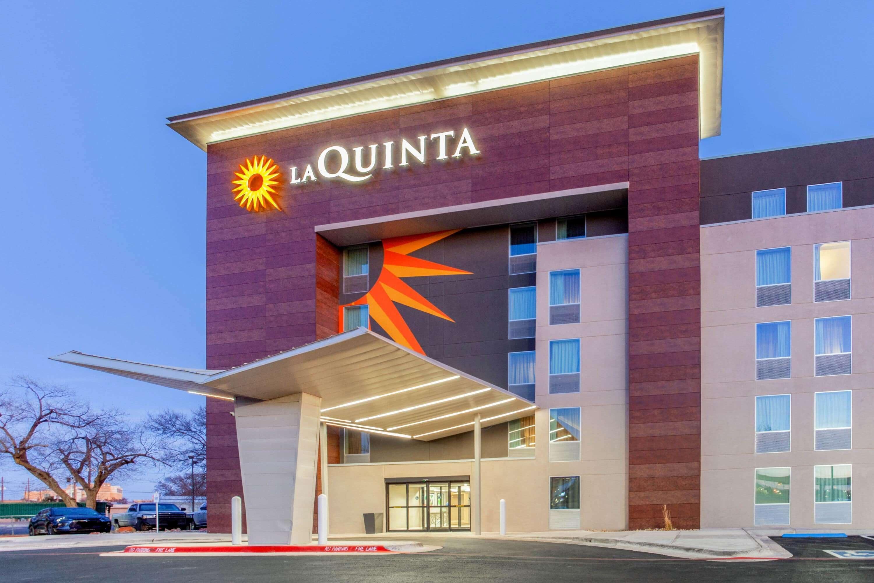 A La Quinta hotel with a prominent sun logo, a covered entrance, and a modern architectural design.