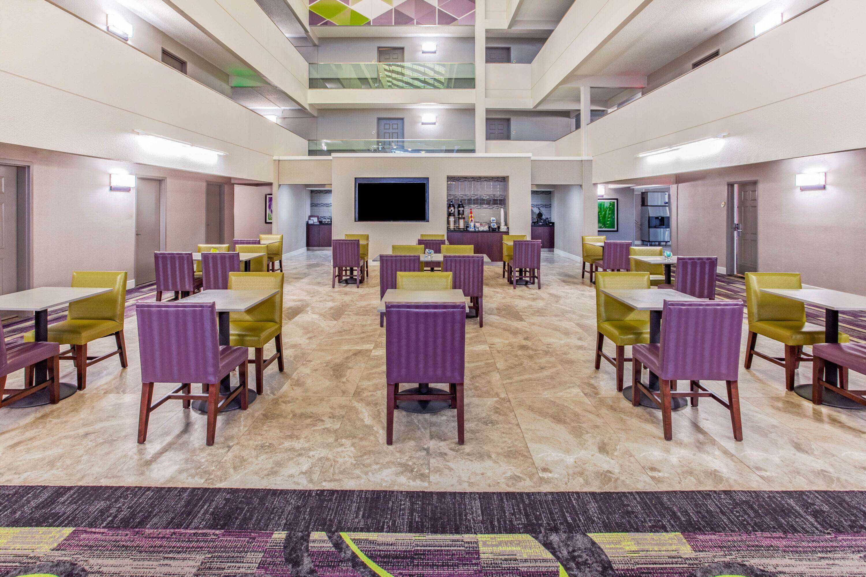 A spacious indoor area with multiple dining tables and chairs, a flat-screen TV, and a bar area.