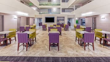 A spacious indoor area with multiple dining tables and chairs, a flat-screen TV, and a bar area.