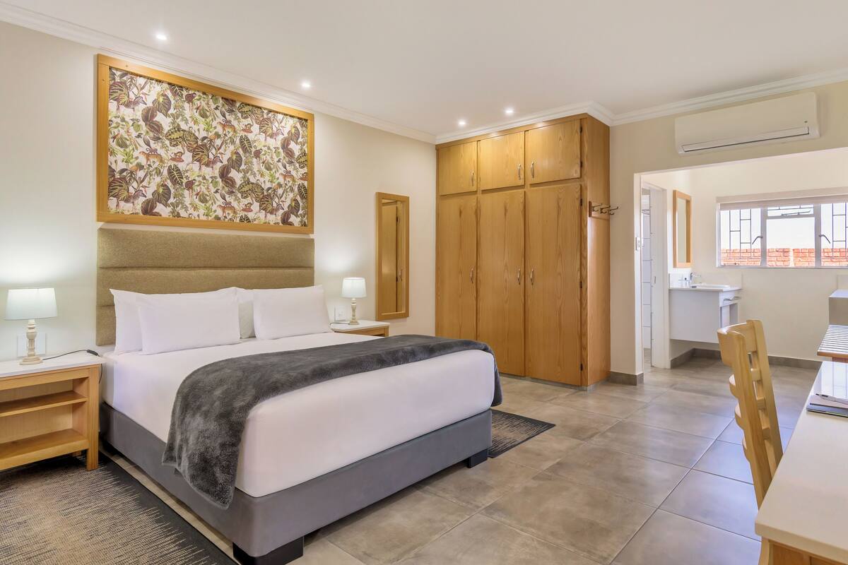 Une chambre d’hôtel avec un grand lit, une armoire en bois et un tableau au mur.