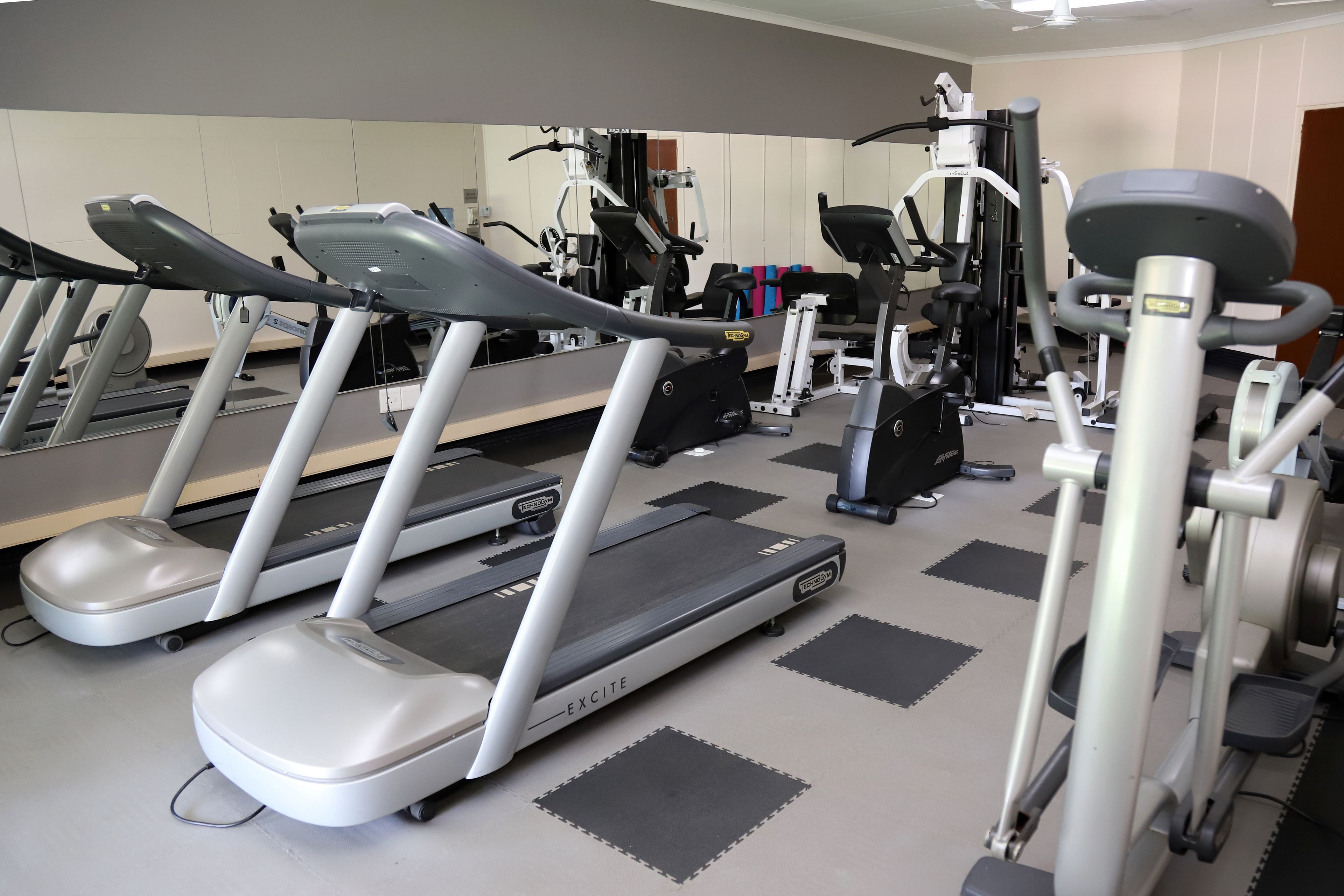 Ein Fitnessstudio mit Laufbändern, Crosstrainern und Krafttrainingsgeräten.