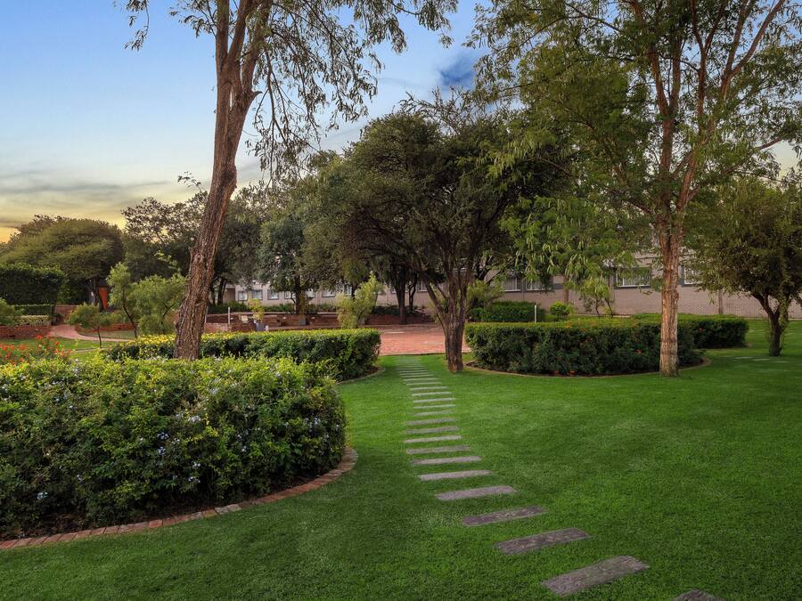 Un jardín bien cuidado con un camino de piedra que lleva a un edificio.
