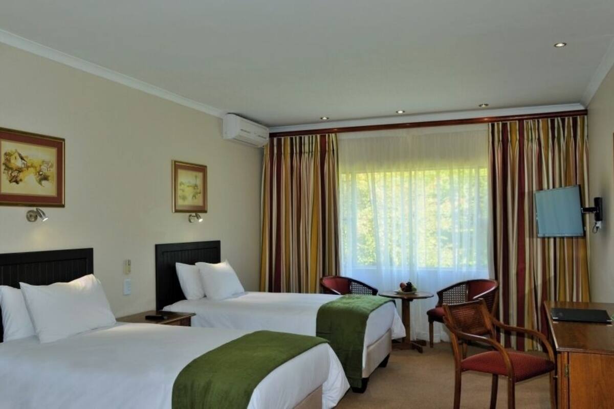 Une chambre d’hôtel avec deux lits, un bureau, une chaise et un téléviseur.